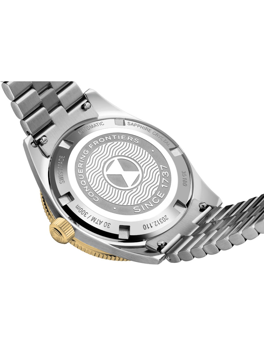 Close-up of a steel metal wristwatch back with a gold crown and linked bracelet, featuring engraved circular design.