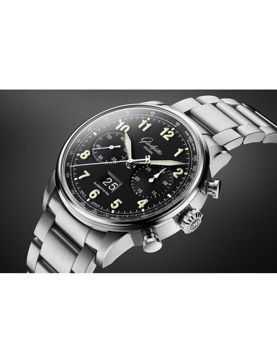 Stainless steel chronograph watch with black dial, luminous Arabic numerals, three subdials, and a date window; angled metal bracelet visible.