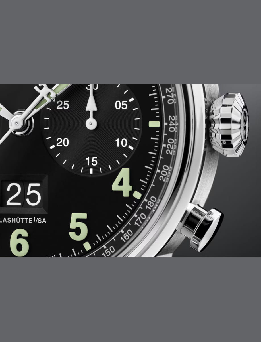 Close-up of a luxury chronograph watch dial showing large mint-green numbers and a date window reading 25, with a metallic crown visible on the right edge.
