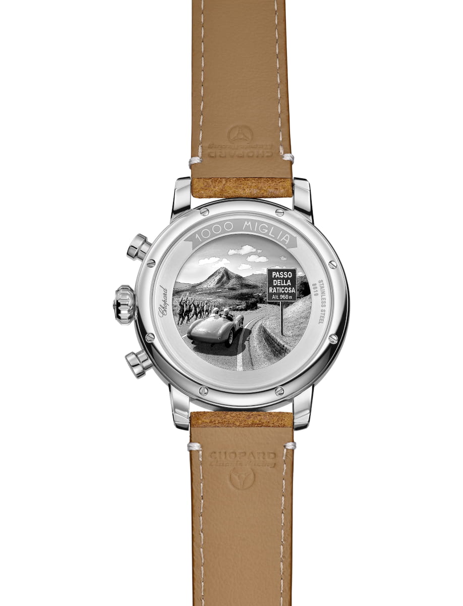 Back of a Chopard Mille Miglia watch with a tan leather strap; metal case back shows a race-scene engraving and a 'Passo della Raticossa' sign engraving.
