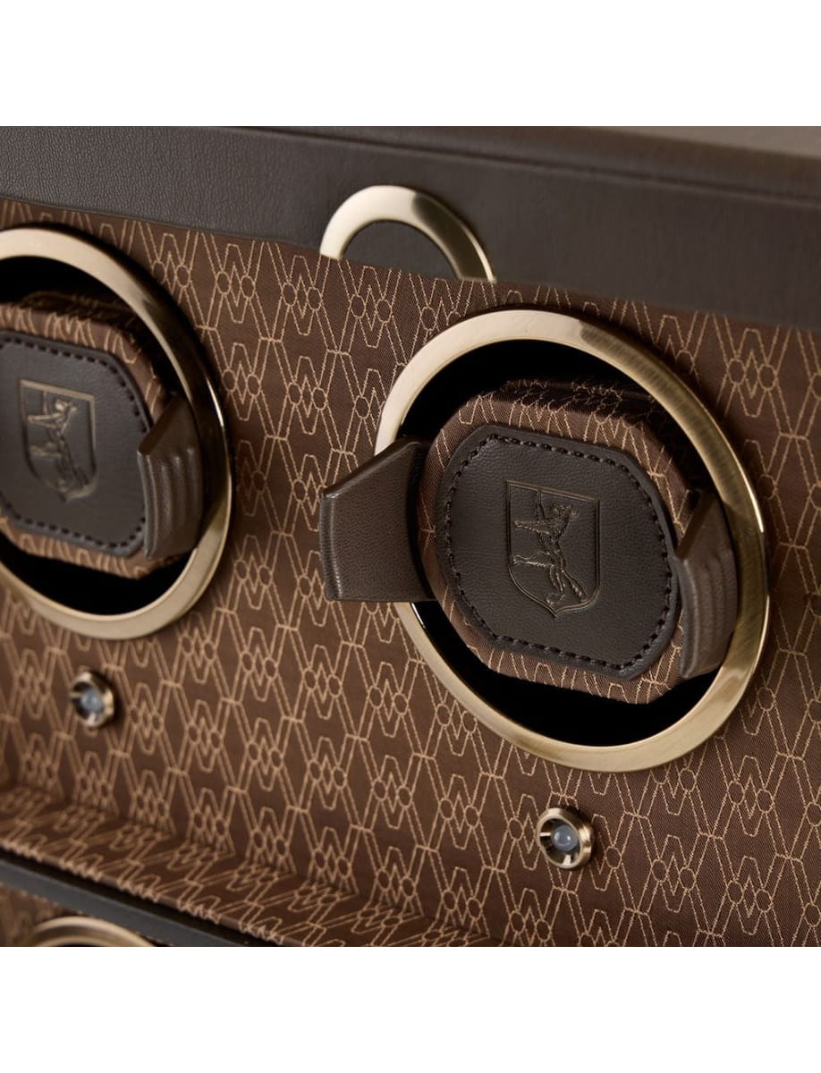 Close-up of a brown patterned luxury handbag with gold circular ring handles and dark leather accents.
