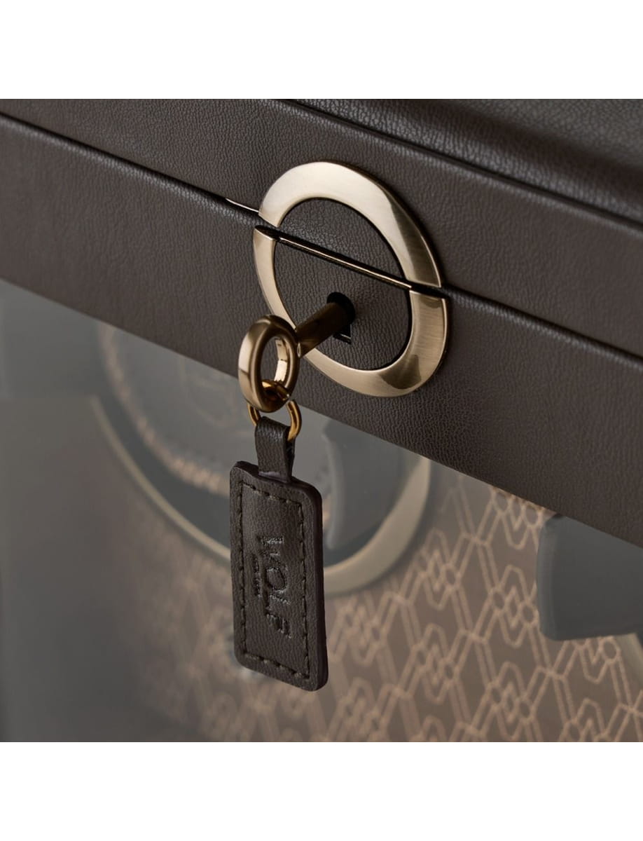 Close-up of a gold circular lock on a black suitcase with a key inserted.