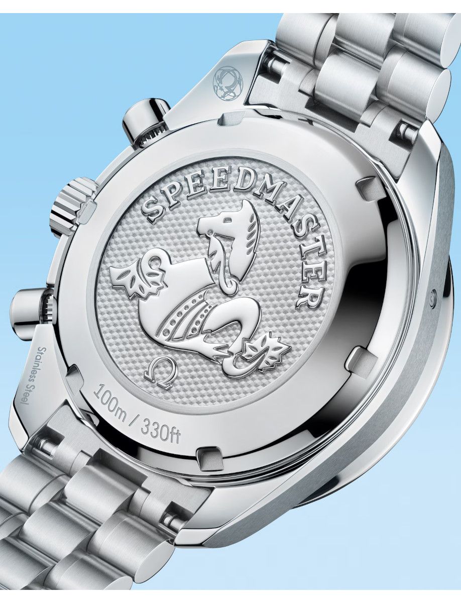 Back of a stainless steel Omega Speedmaster watch with the seahorse emblem and '100m / 330ft' engraving against a light blue background.