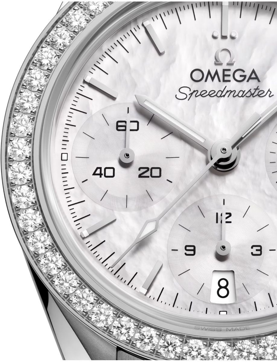 Close-up of an Omega Speedmaster wristwatch with a diamond-studded bezel and white mother-of-pearl dial, showing subdials and date window at 8 o'clock location