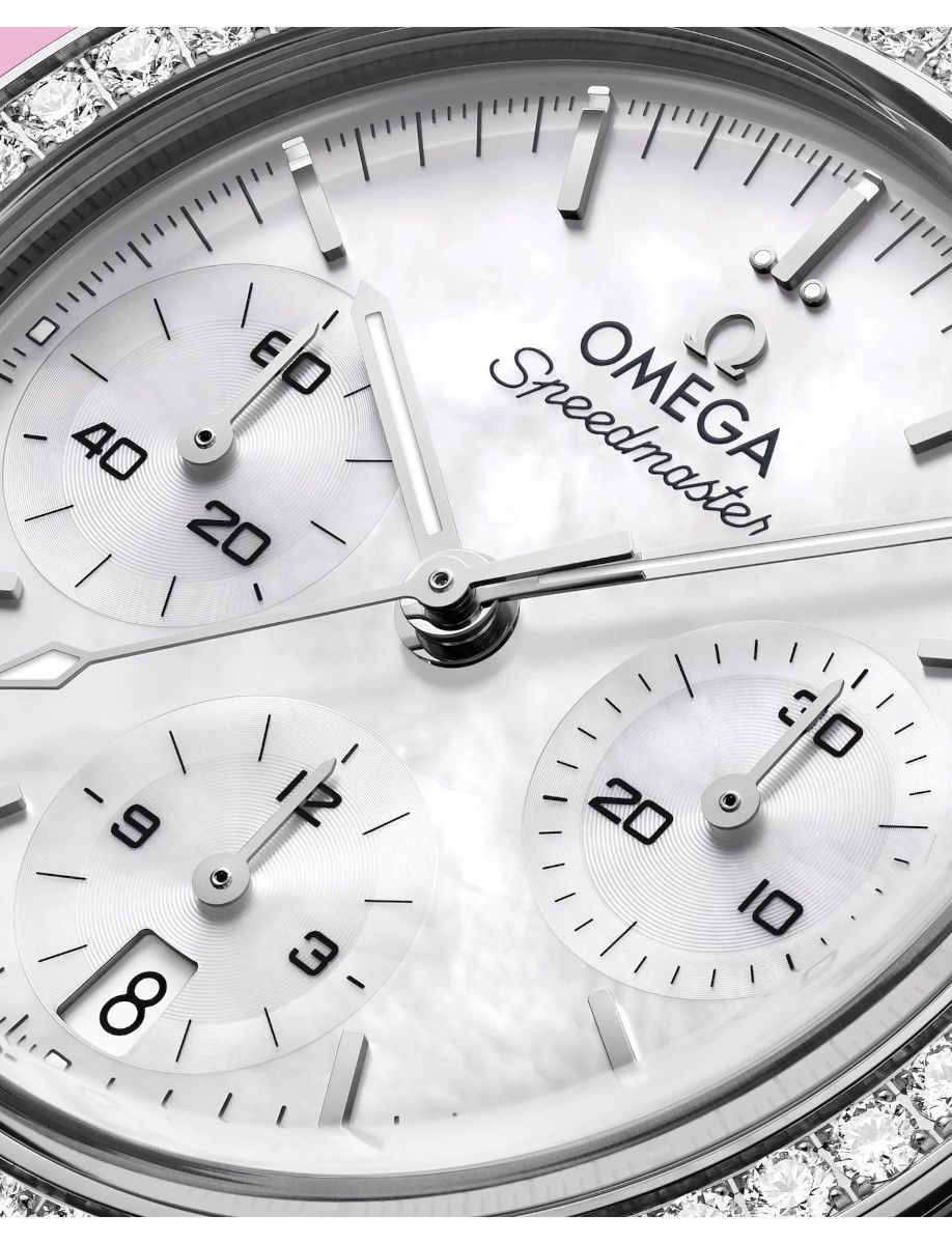 Close-up of an Omega Speedmaster watch face with three subdials, silver hands, and a diamond-studded bezel.