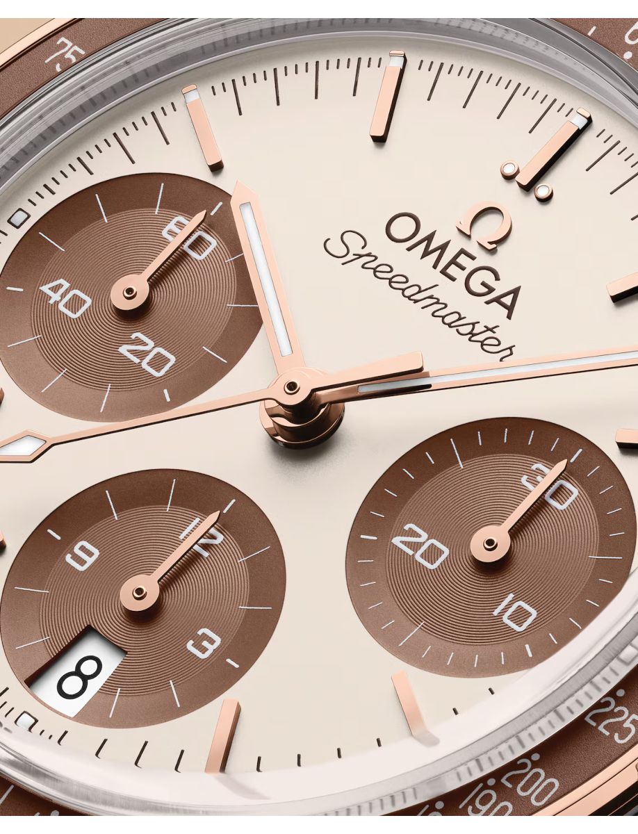 Close-up of an Omega Speedmaster luxury chronograph dial in rose gold, featuring three brown subdials and a date window at 8 o'clock