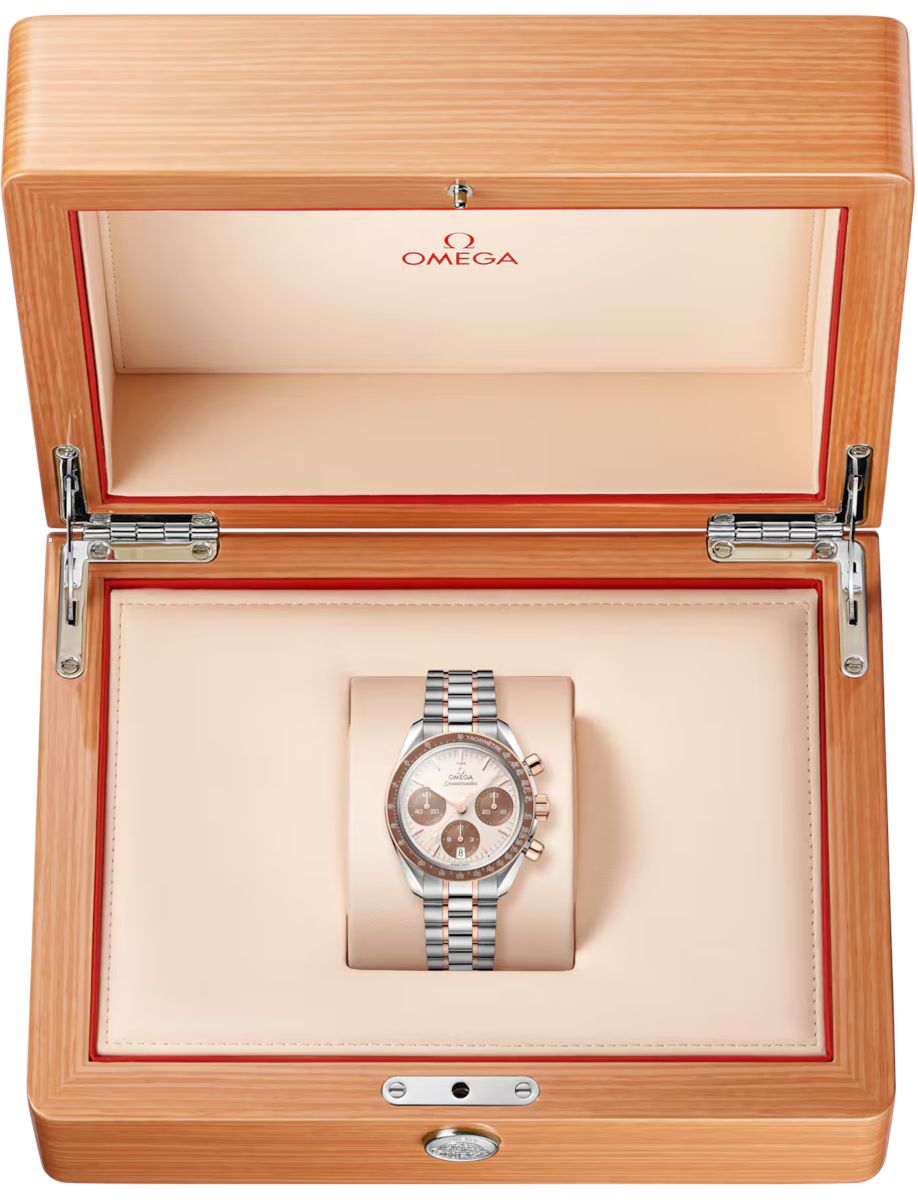 Omega watch in open wooden display box with cream interior and red trim, showcasing a two-tone bracelet and chronograph dial.