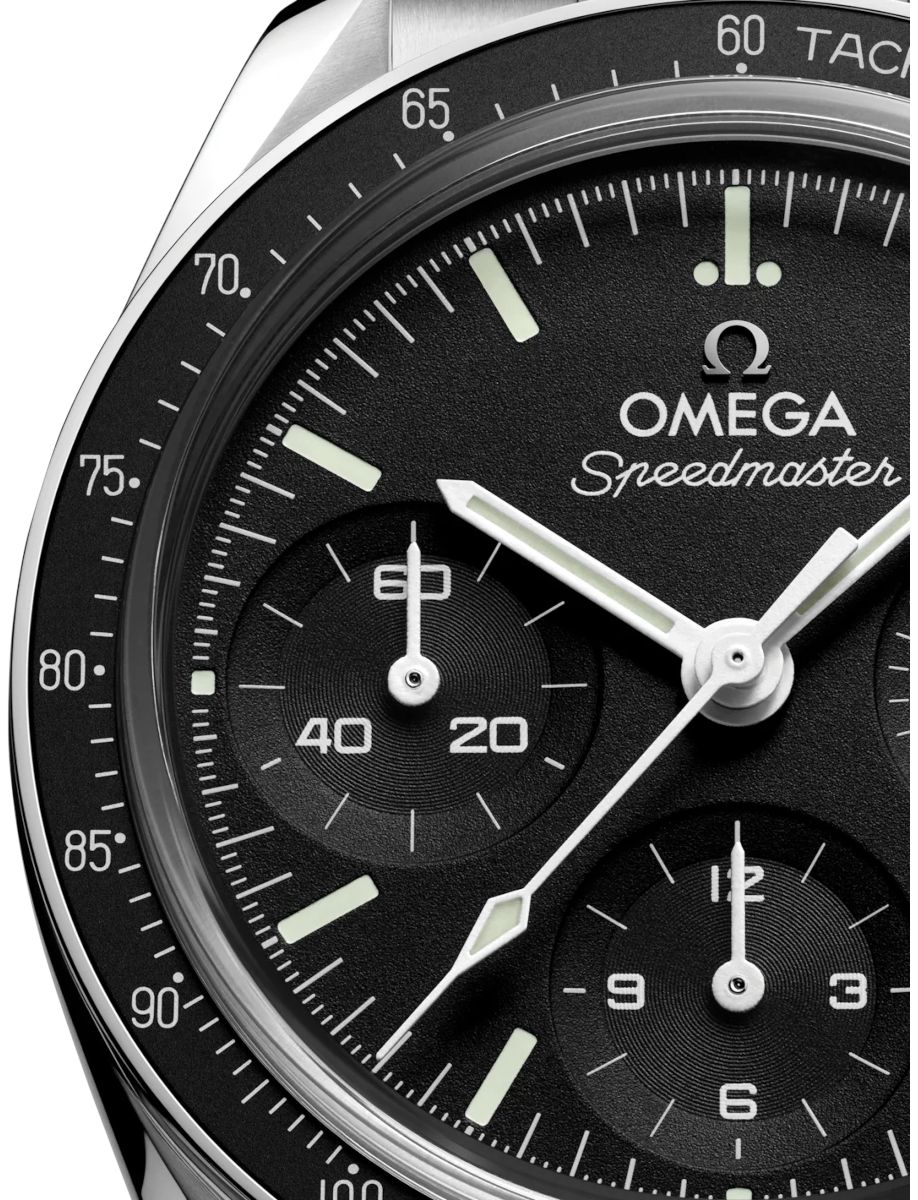 Close-up of an Omega Speedmaster watch dial showing subdials, markers, and the Omega logo on a black face.
