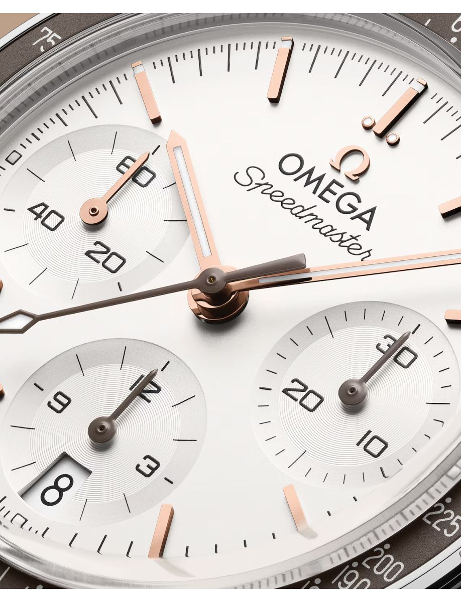 Close-up of an Omega Speedmaster watch dial with rose-gold hands and three subdials showing 60, 30, and 12/20 tick marks, branding visible