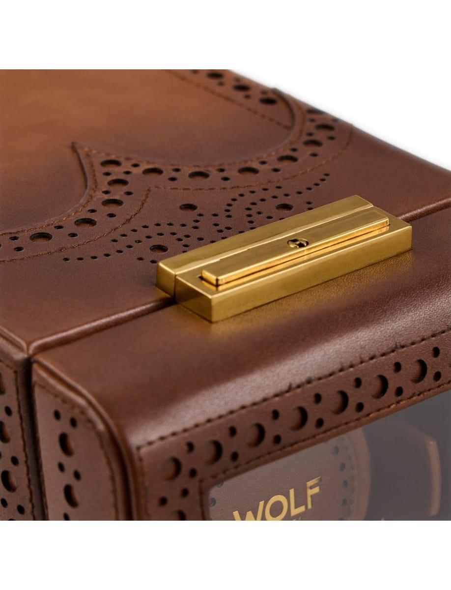 Close-up of a brown leather case with brogue perforations and a gold rectangular clasp.