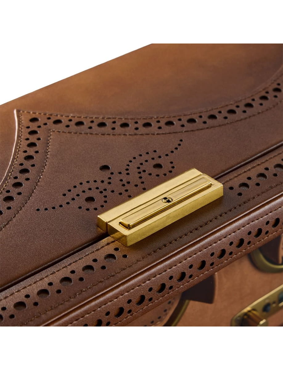 Close-up of brown leather bag with brass latch and perforated decorative pattern.
