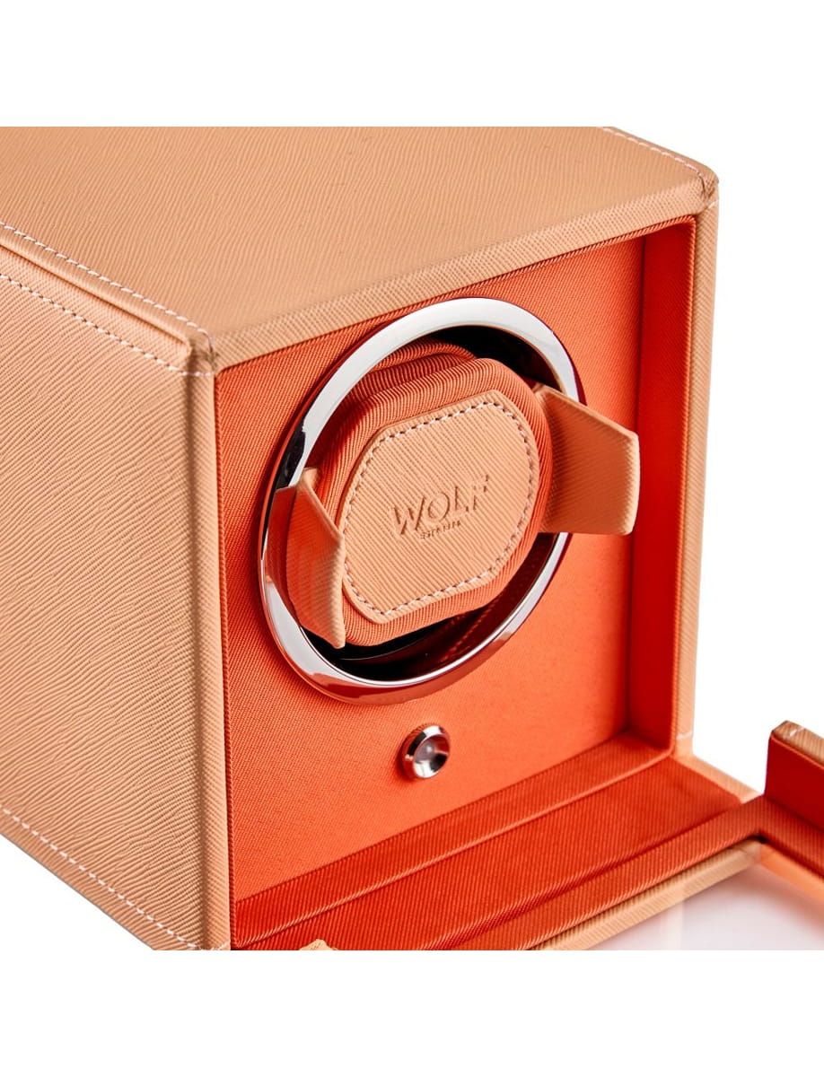 Open tan leather box revealing an orange interior with a circular chrome watch winder and padded orange cushion labeled WOLF.