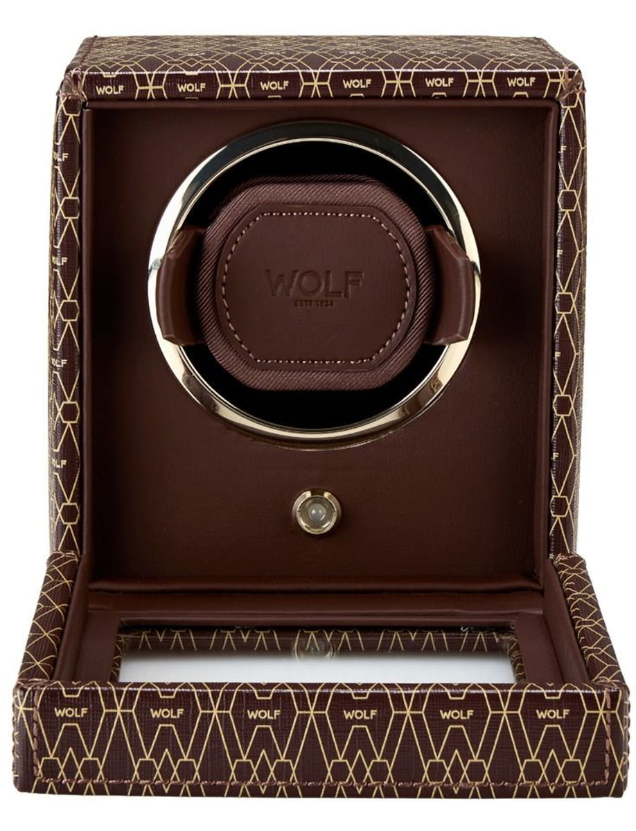 Open gift box revealing a brown Wolf watch winder with a circular chrome ring and brown leather cushion inside.