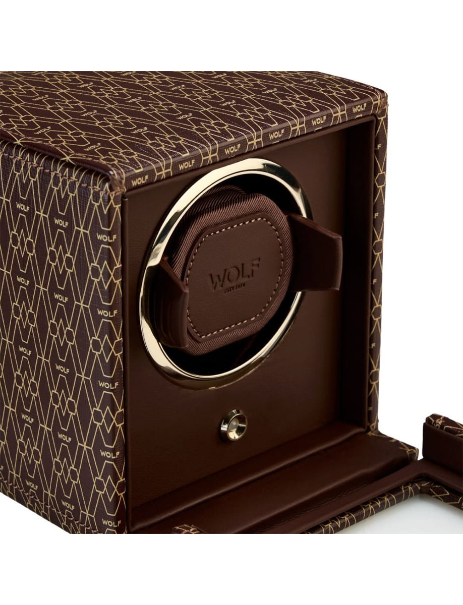 Brown leather Wolf watch winder in a patterned brown box with a gold ring and embroidered WOLF branding on the lid edge.