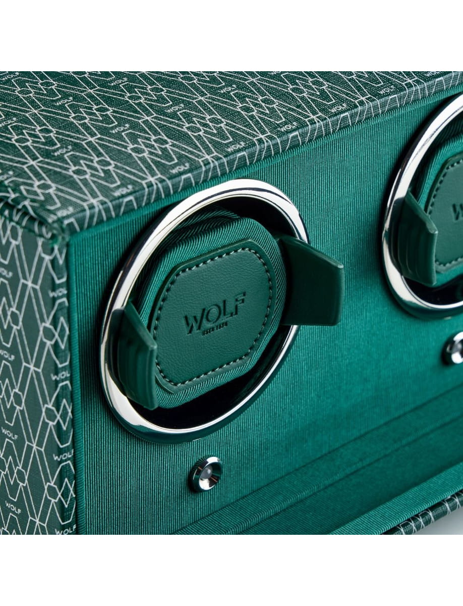 Close-up of a teal suitcase corner with circular chrome handle rings and green leather pads branded WOLF.