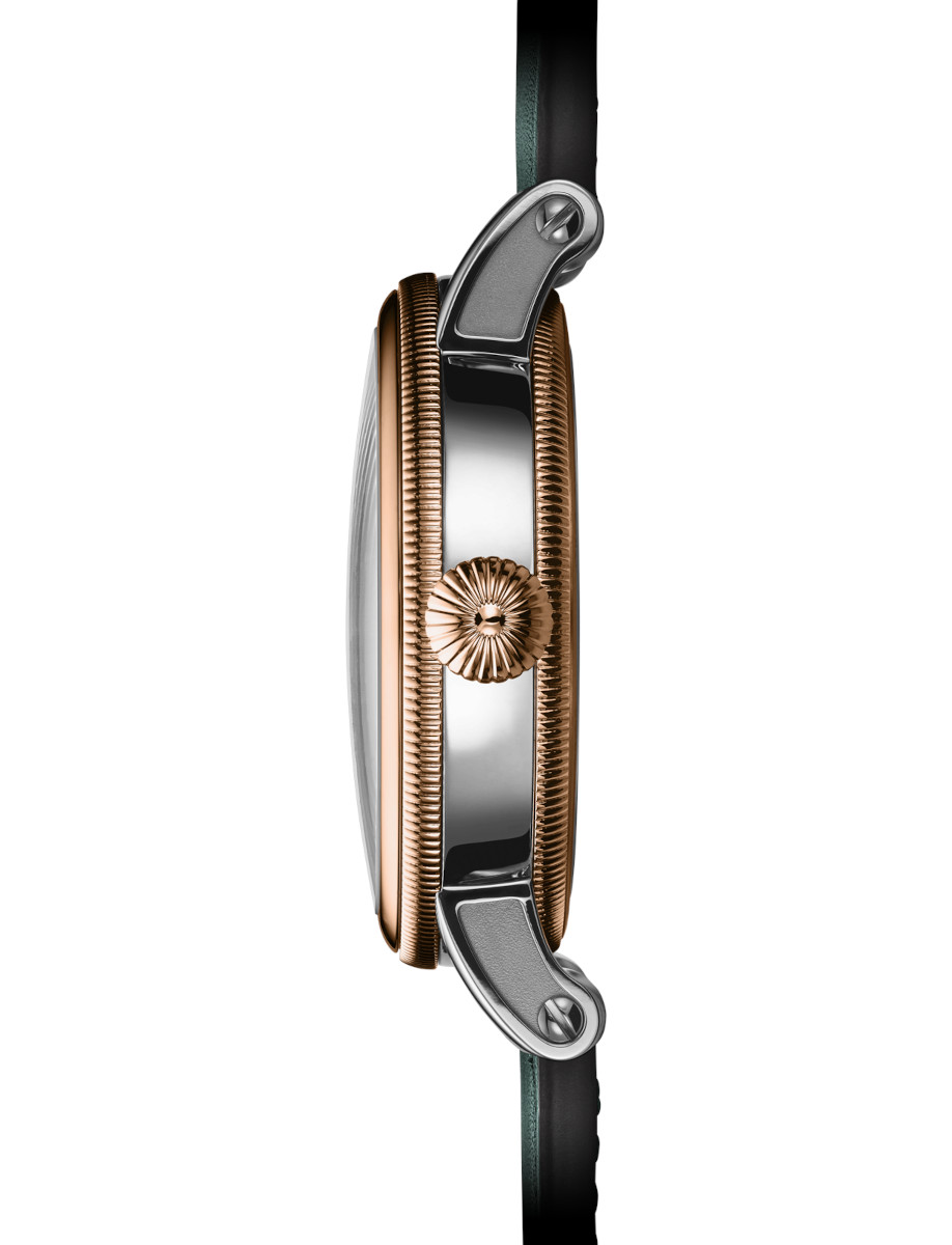 Close-up side view of a two-tone wristwatch with a gold bezel and textured crown.