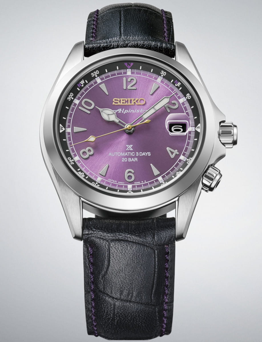 Close-up of a stainless steel Seiko wristwatch with a purple dial, black leather strap with purple stitching, and a date window at 3 o'clock.