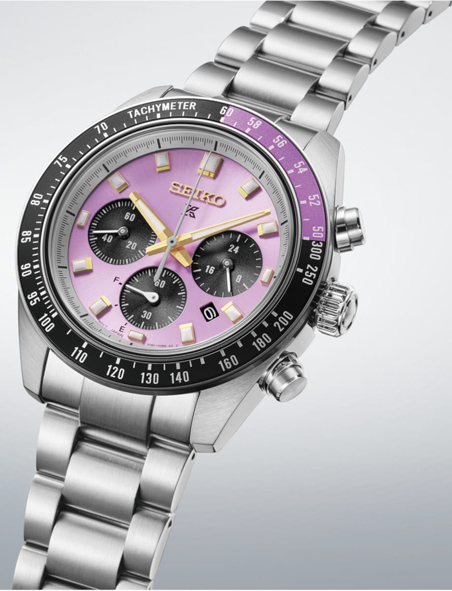 Seiko chronograph wristwatch with a purple dial, black tachymeter bezel, and silver metal bracelet.