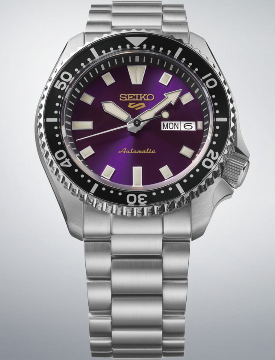 Stainless steel Seiko watch with a purple dial and black bezel, showing day and date.