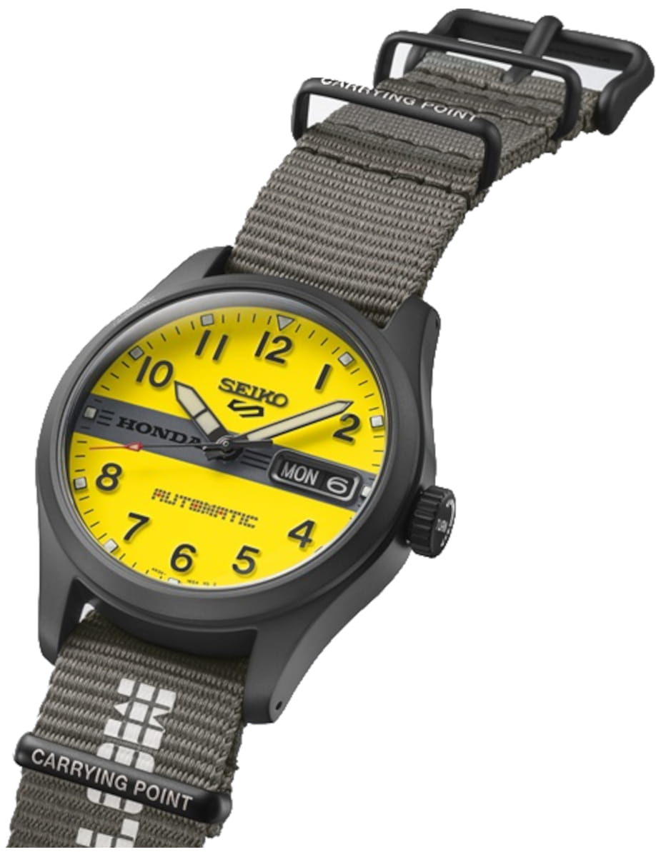 Yellow-dial Seiko 5 automatic watch with black case and gray NATO strap; day-date window and branding visible on dial and strap