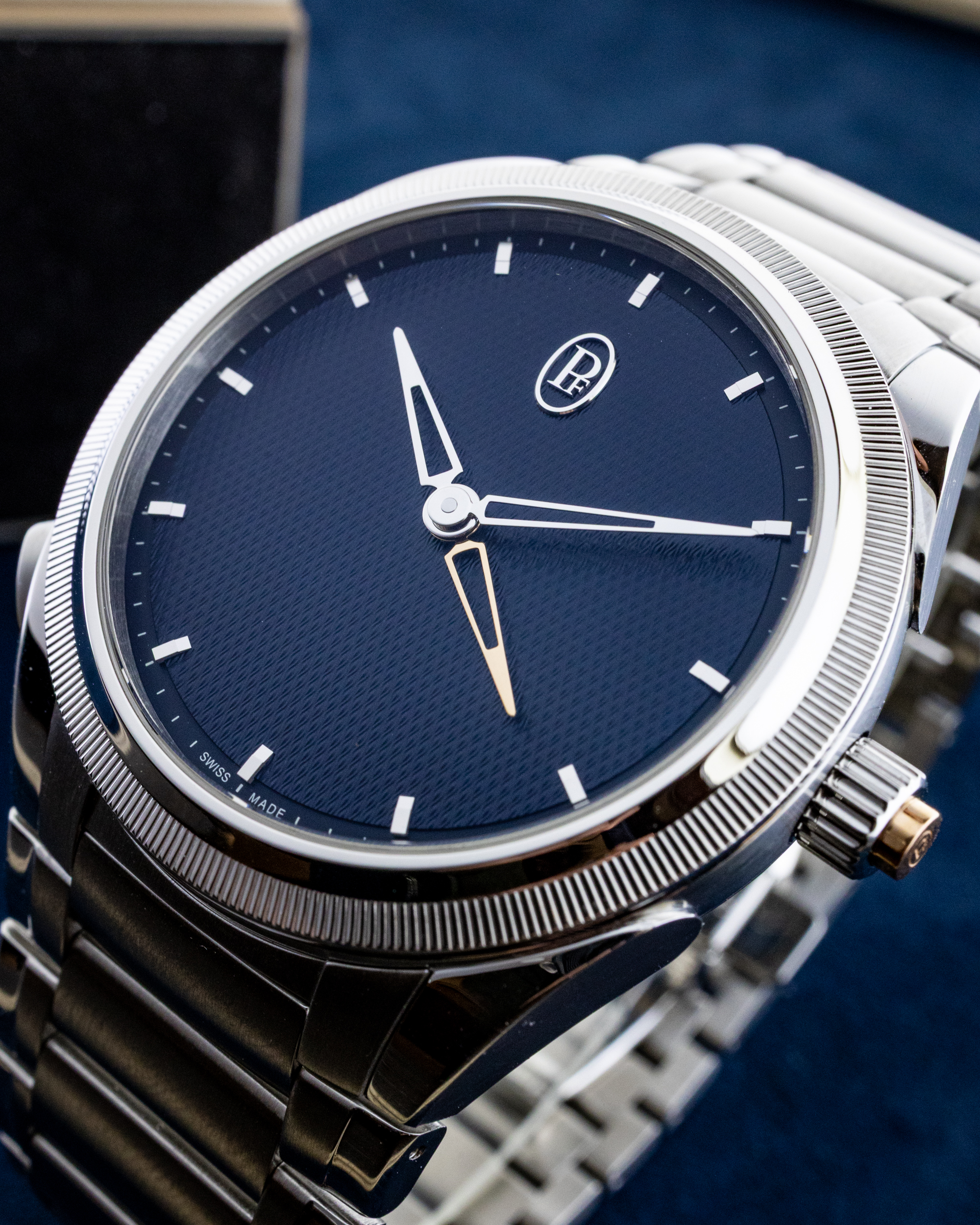 Close-up of a blue dial wristwatch with a silver bezel and metal link bracelet.