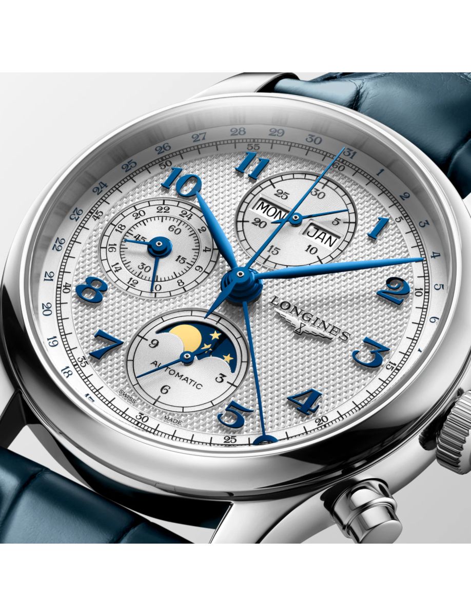 Close-up of a silver wristwatch with blue hands and multiple subdials showing date, day, month, and moon phase (Longines).