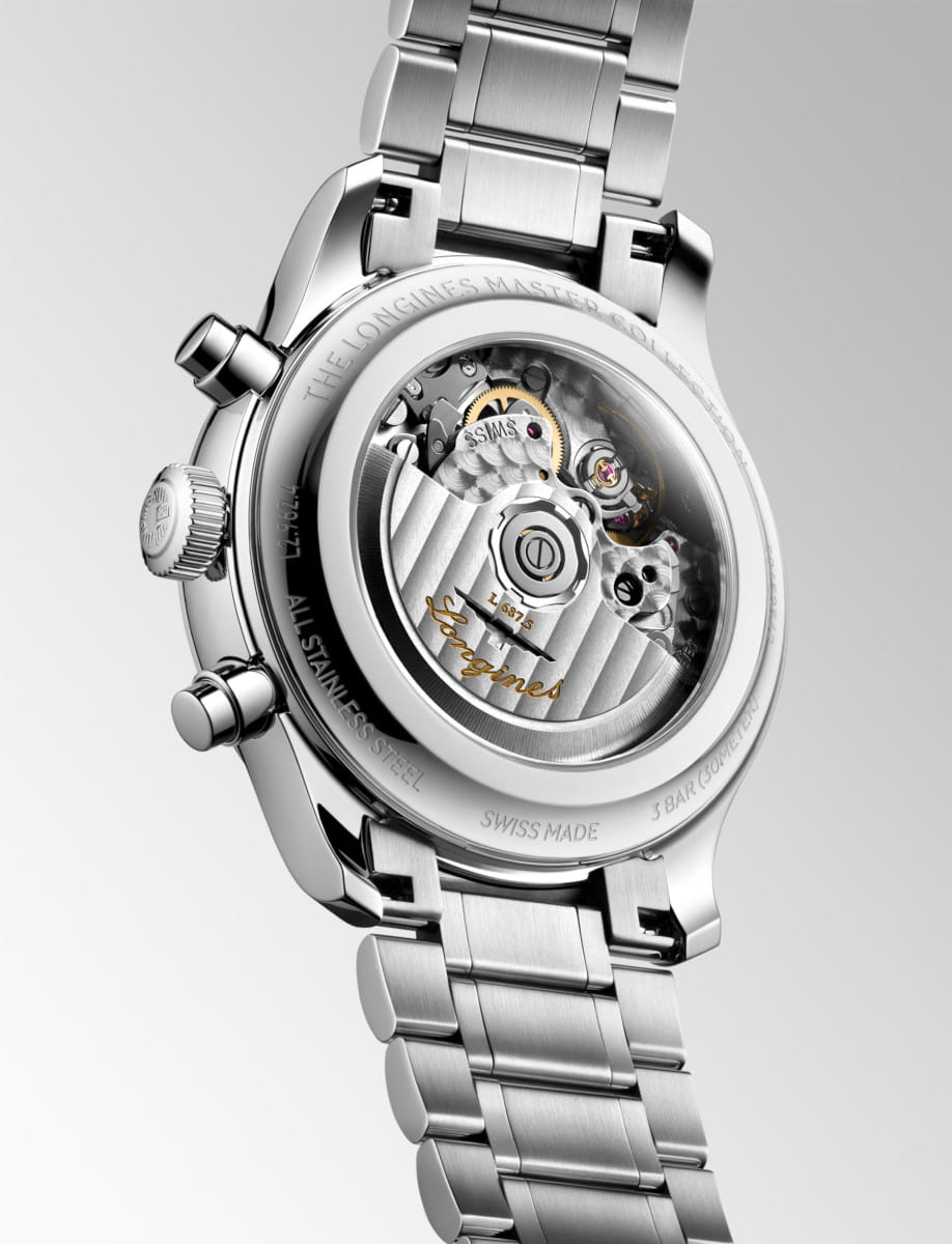 Close-up of a stainless steel wristwatch showing its transparent case back with visible gears and rotor for the movement function.