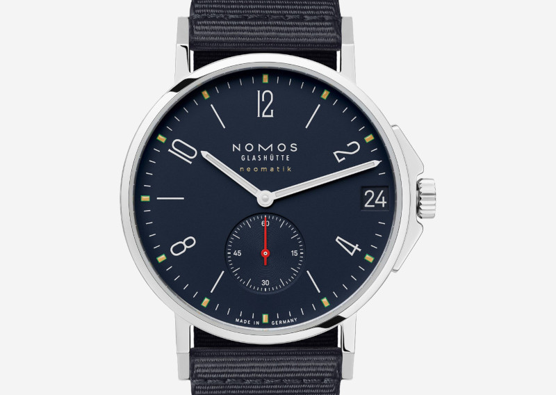 Nomos Glashütte Neomatik wristwatch with a dark blue dial, silver case, white hands, and navy fabric strap; subdial at 6 and date at 3 o'clock.