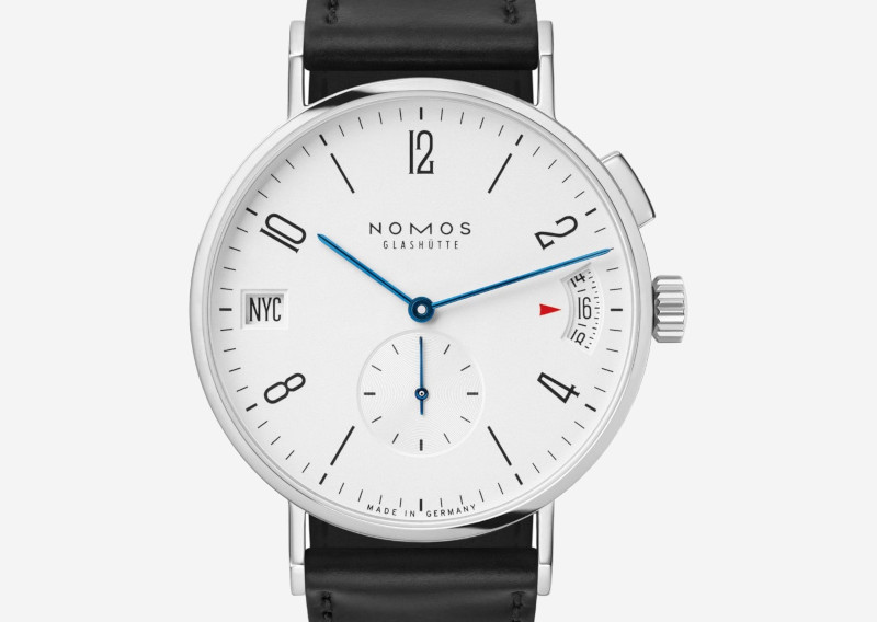 Nomos Glashütte wristwatch with white dial, blue hands, black leather strap and NYC date window on the left.