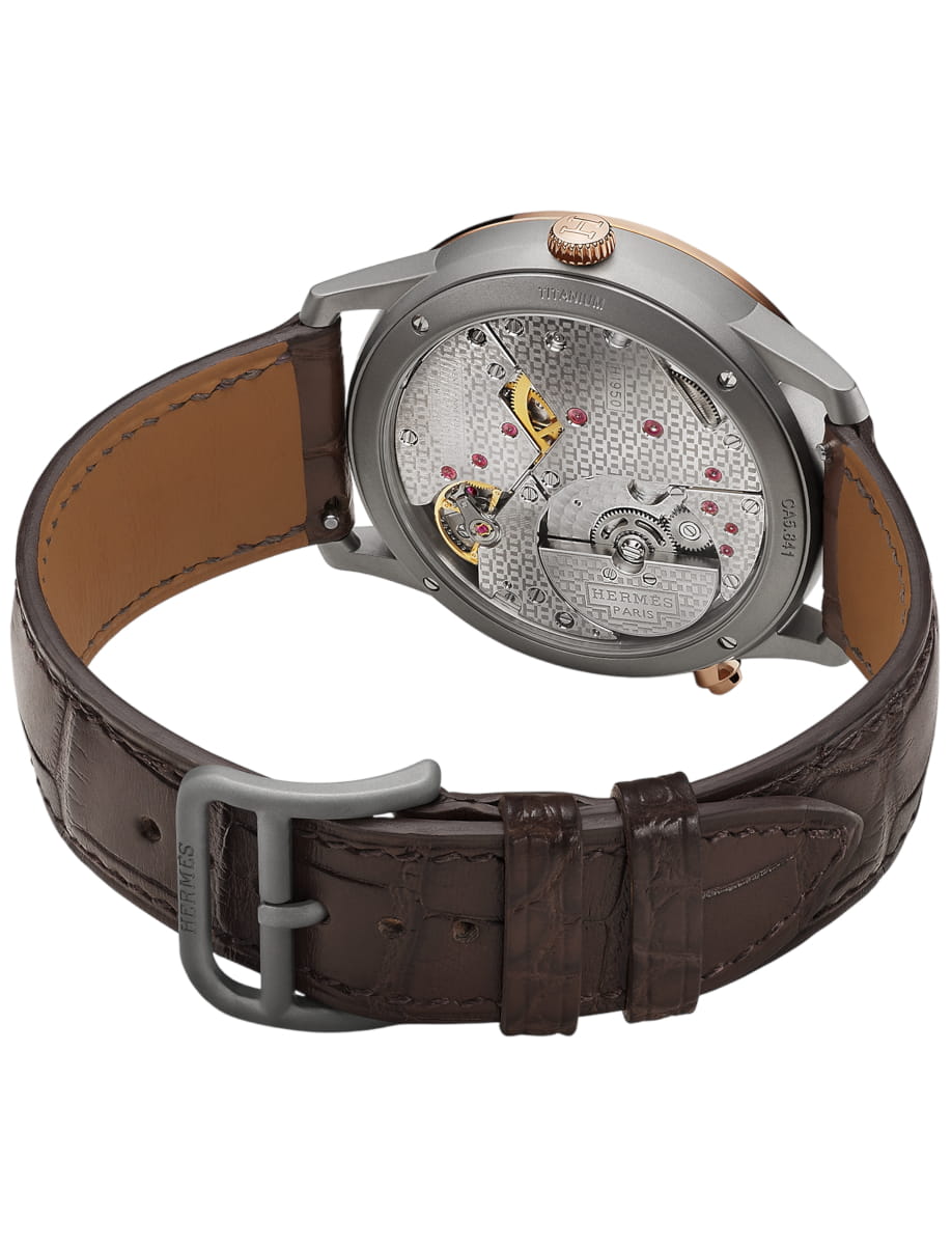 Hermès wristwatch with a brown leather strap and a transparent case back showing the mechanical movement and jewels.