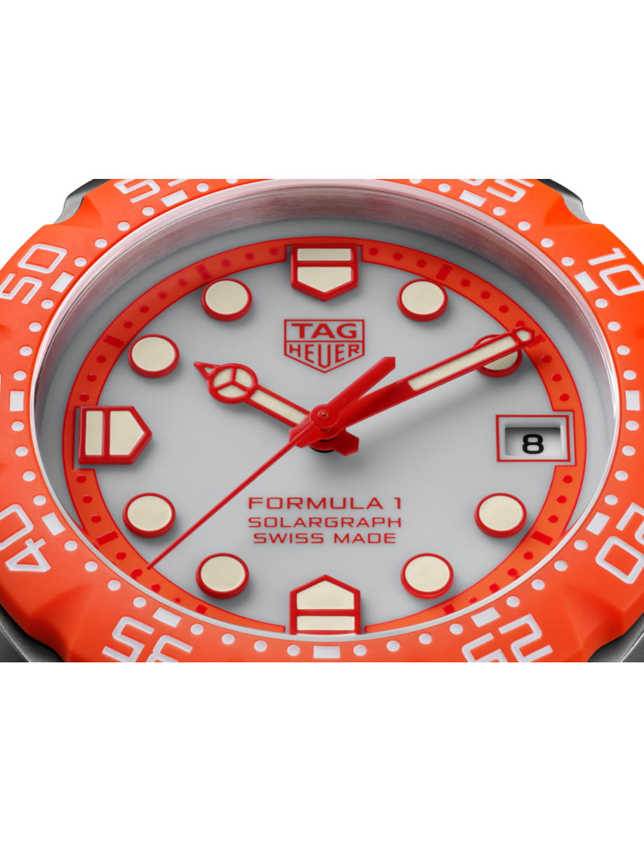 Orange bezel TAG Heuer Formula 1 watch with grey dial, red hands, and date window at 3 o'clock