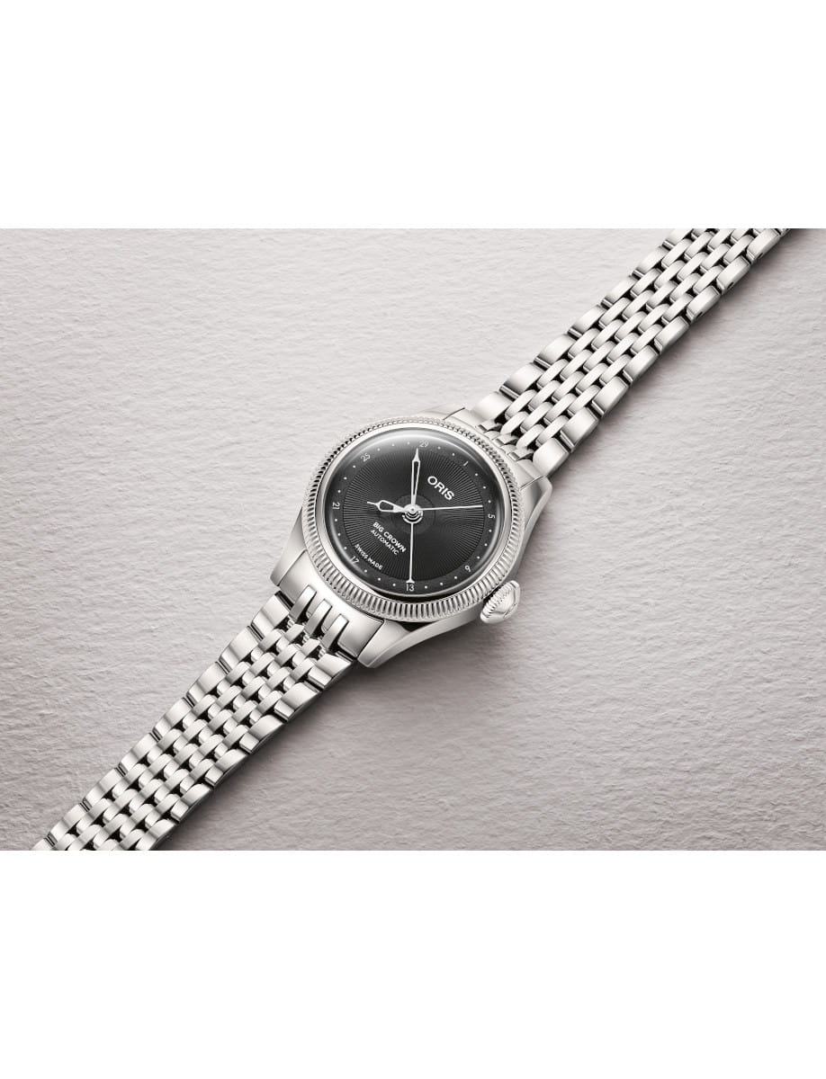 Oris stainless steel wristwatch with a black dial and silver bracelet on a light textured surface