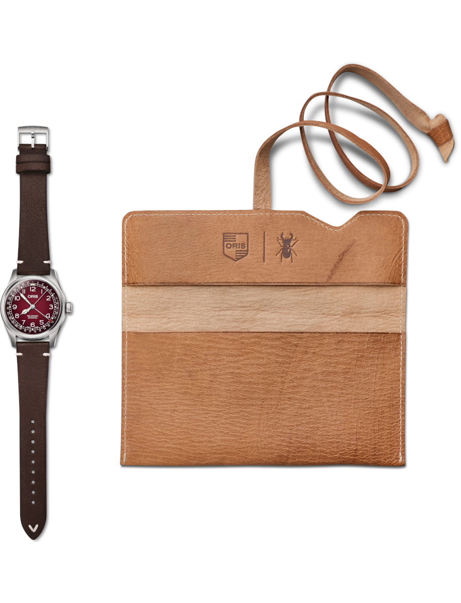 Oris brown leather-band wristwatch with a burgundy dial beside a travel pouch in Cervo Volante sustainable deer leather