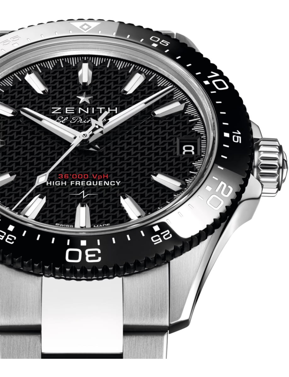 Close-up of a Zenith El Primero wristwatch with a black textured dial, white markers, and a stainless steel case and bezel; crown on the right.