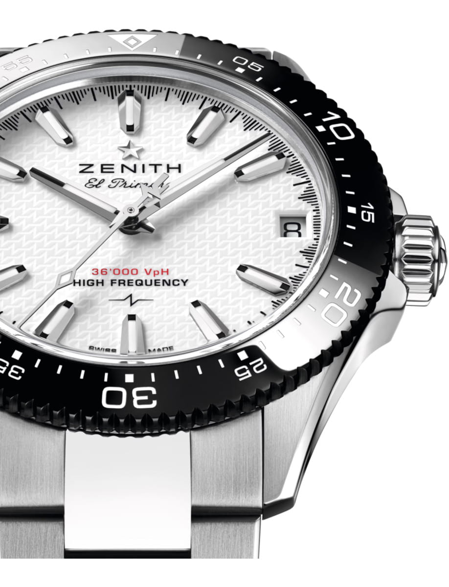 Close-up of a Zenith El Primero wristwatch: white ceramic dial, bold hour markers, black ceramic bezel, date window at 3 o'clock, and stainless steel bracelet.