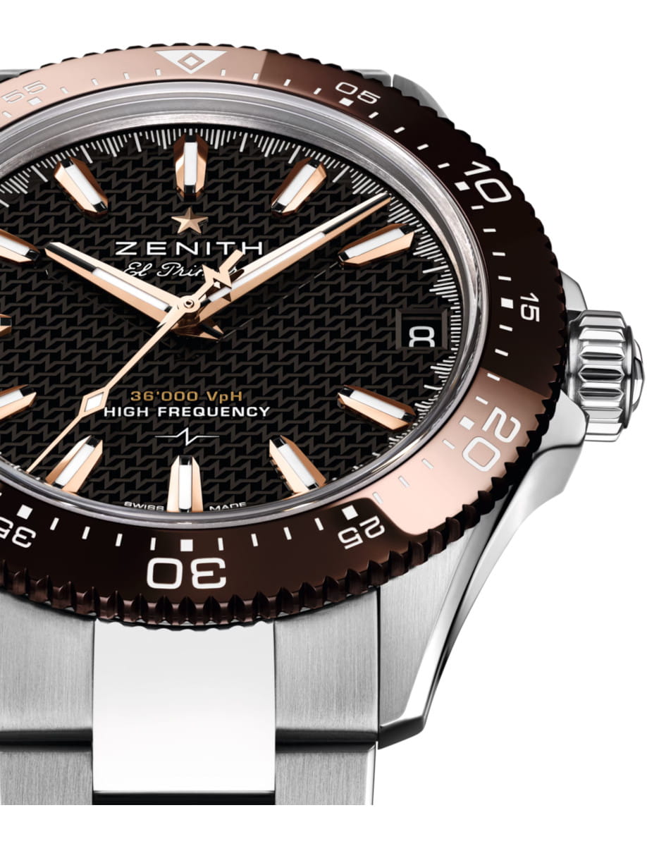 Close-up of a Zenith El Primero wristwatch with a black textured dial, rose-gold markers, and a two-tone brown bezel on a metal bracelet