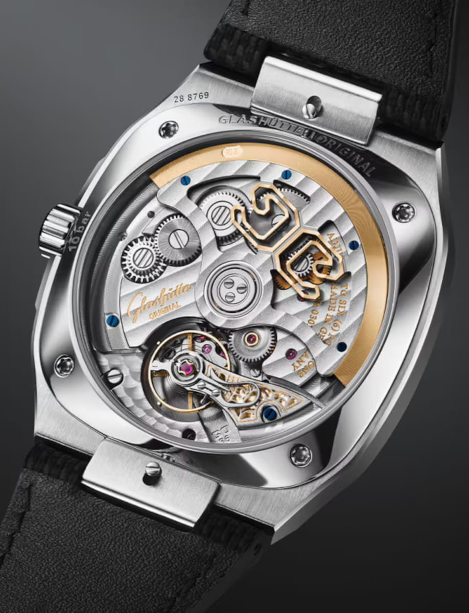 Exposed mechanical watch movement with gears and gold accents, seen through a transparent case back of a luxury timepiece.