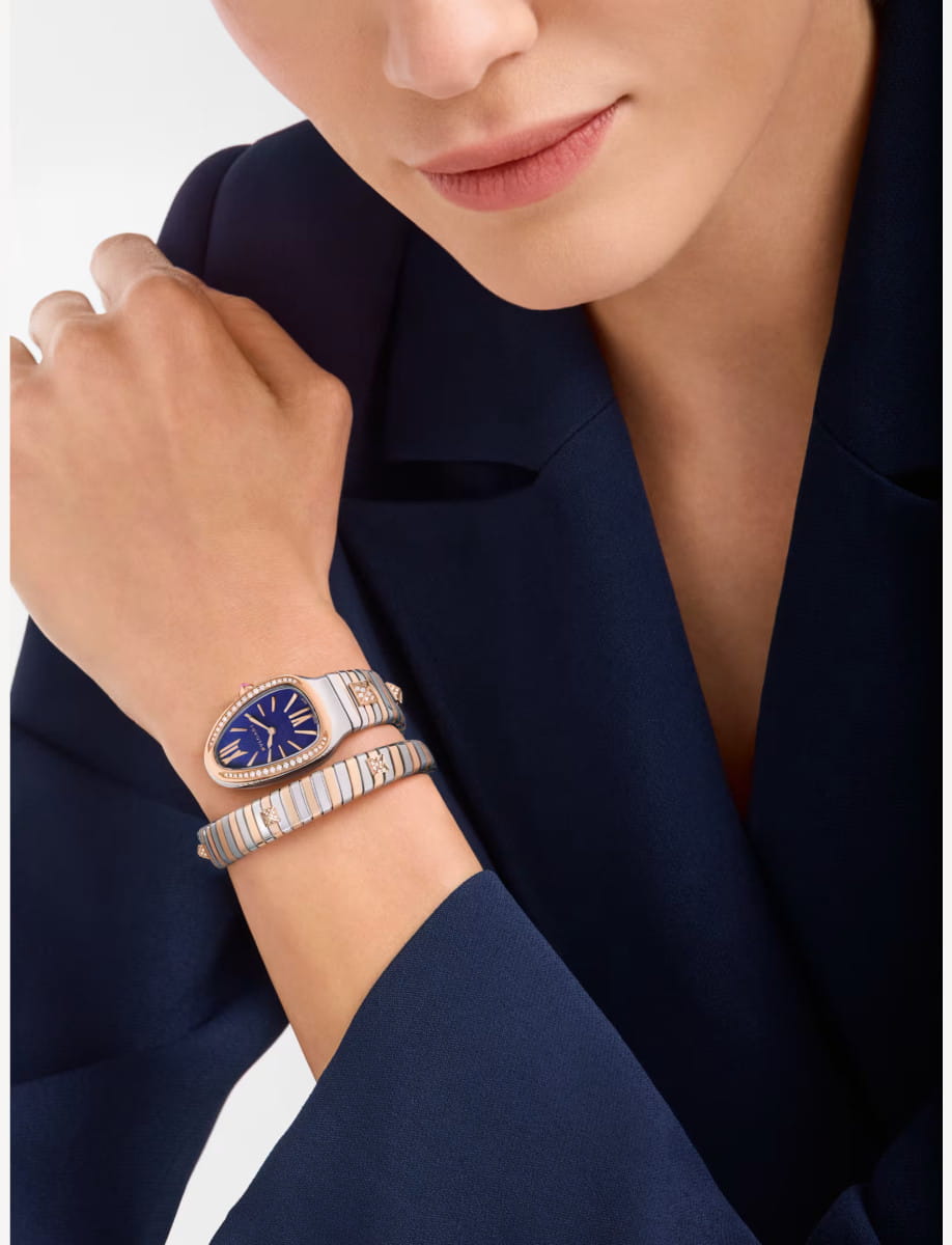 Close-up of a woman's wrist wearing a Bulgari Serpenti watch with a blue dial, rose gold and stainless steel case and bracelet, diamond-set bezel and accents