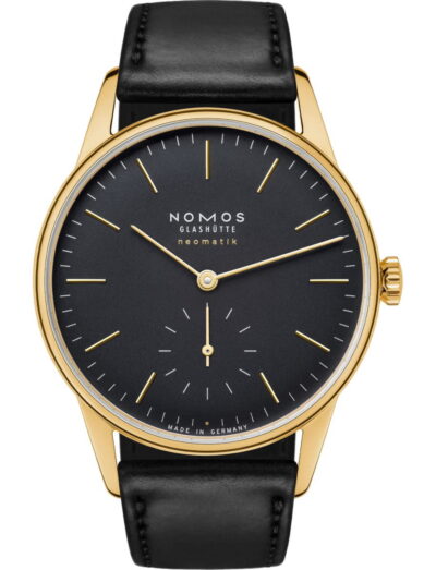 Gold-toned Nomos Glashütte wristwatch with a black dial, gold hour markers, and a black leather strap (Made in Germany).