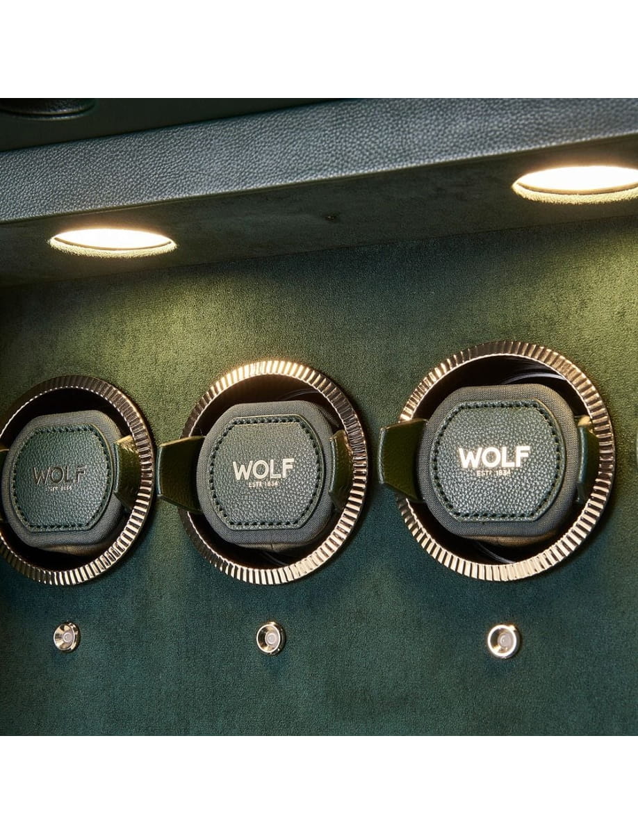 Three Wolf watch winders set in a dark green display cabinet under overhead lights, showing the brand.