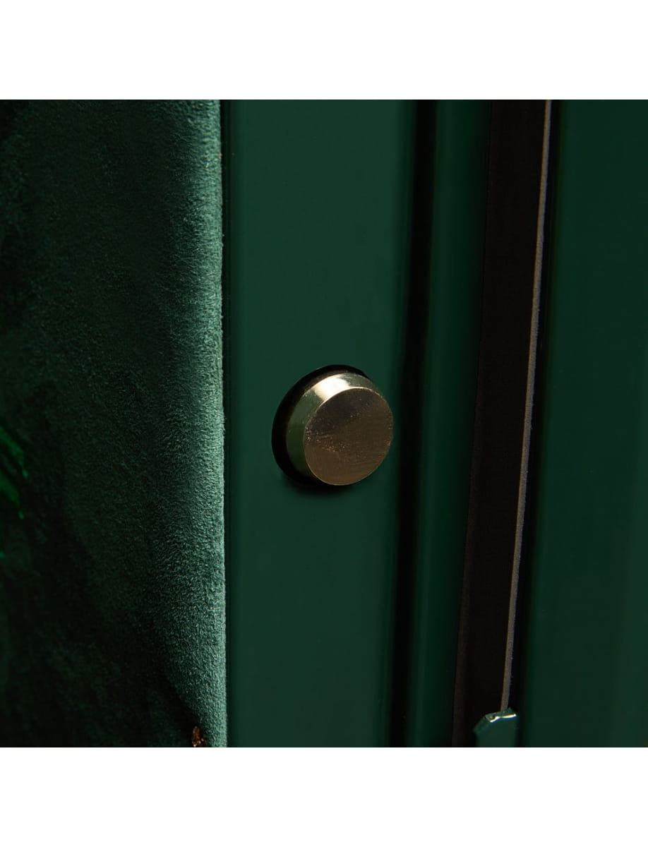 Close-up of a brass door knob on a dark green door, viewed from the side