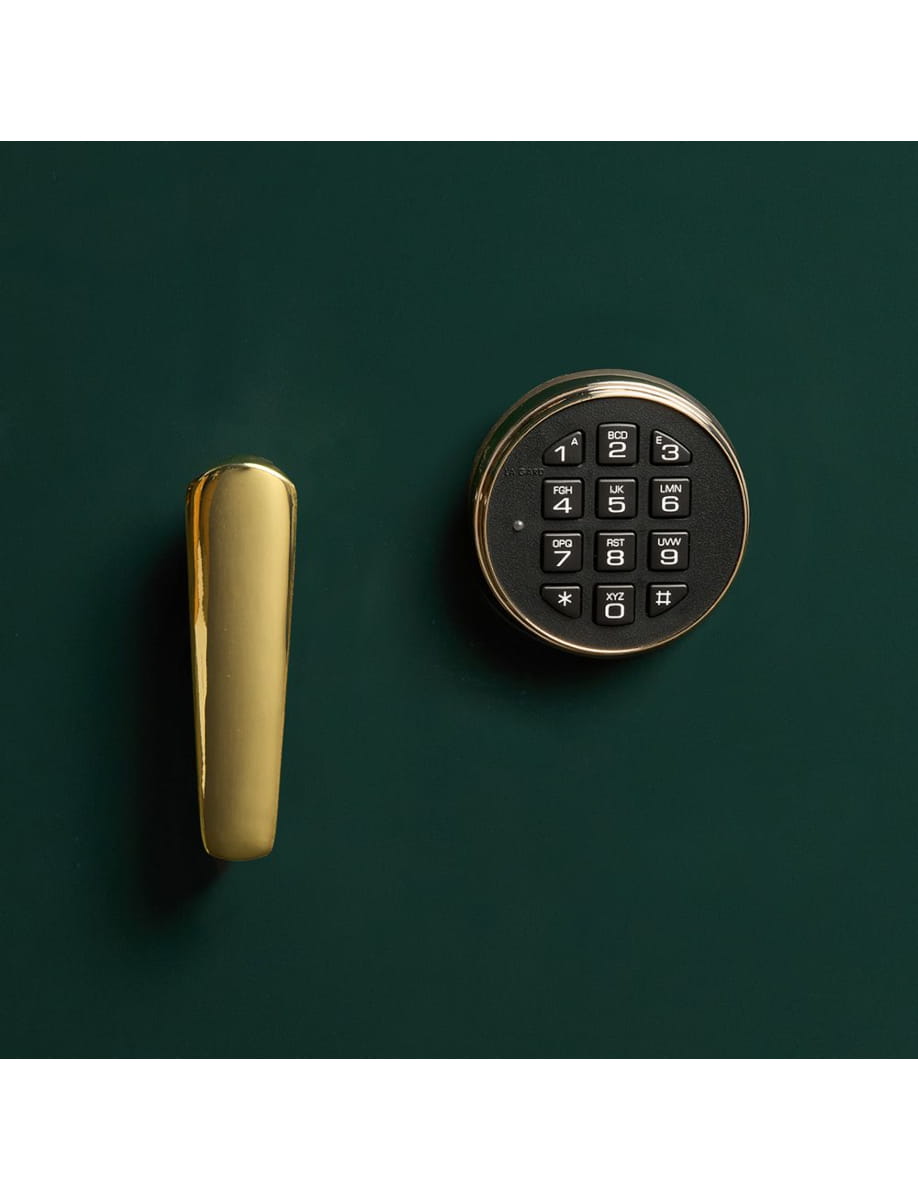 Gold-colored circular electronic safe lock with a numeric keypad, mounted beside a vertical gold handle on a dark green surface.