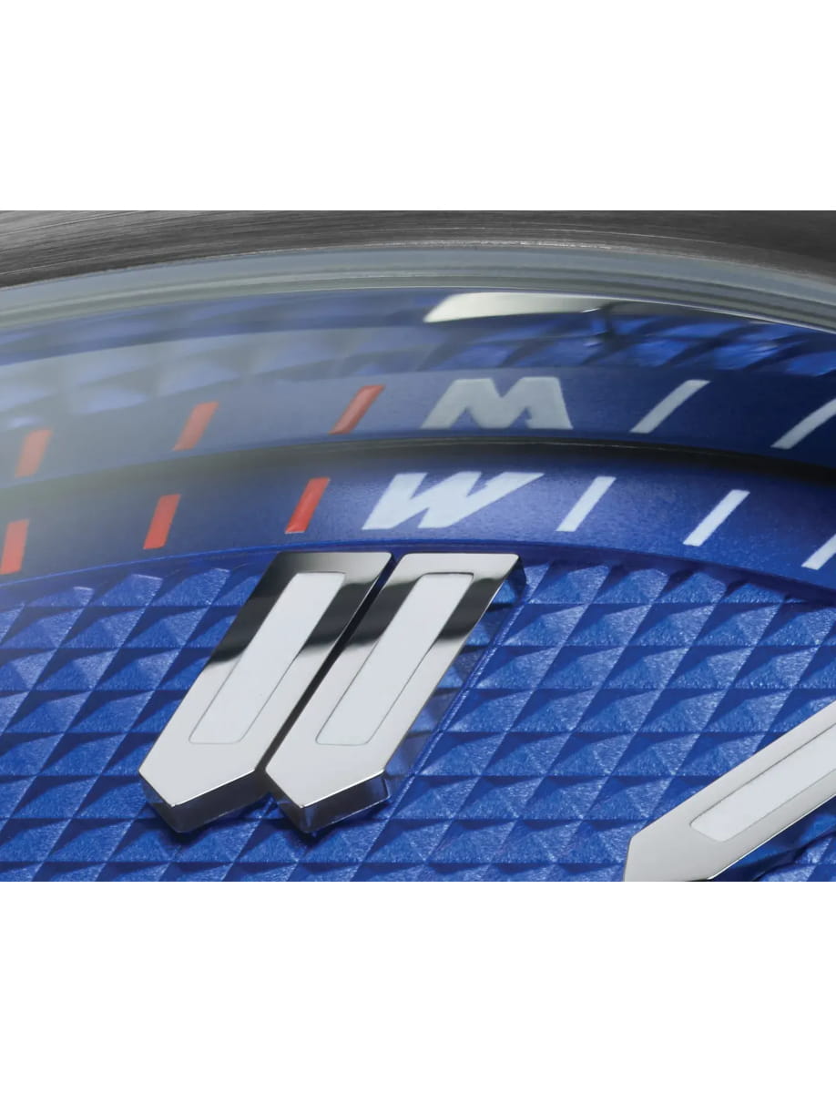 Close-up of a blue textured watch dial with a large silver 'W' logo.