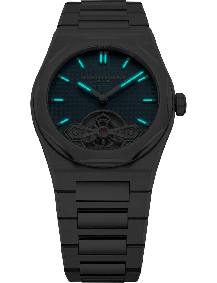 Black matte metal wristwatch with teal luminous hands and hour markers; features an exposed tourbillon at the 6 o'clock position.