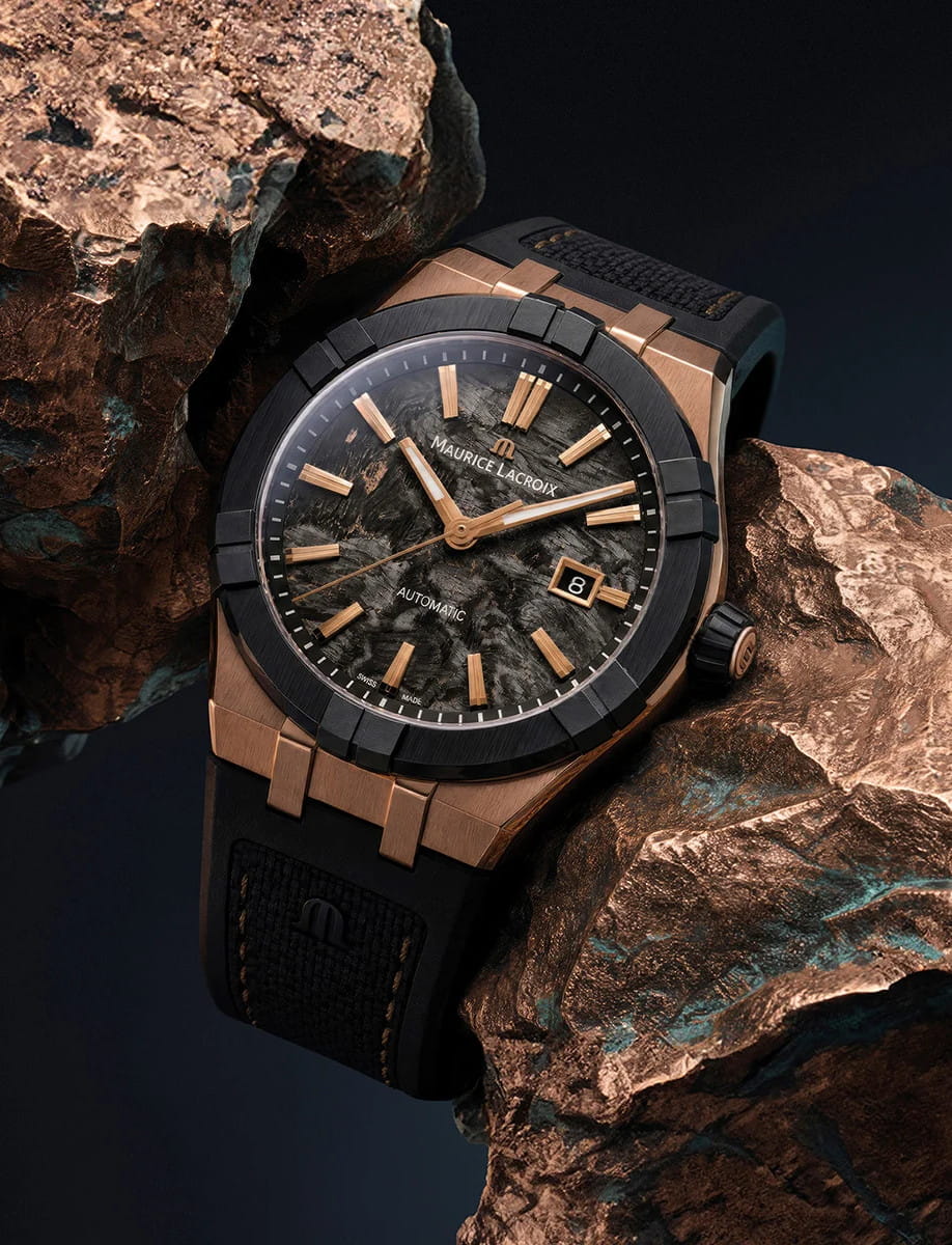Close-up of a Maurice Lacroix automatic wristwatch with a bronze case, bi-rubber strap with imitation nylon-textured rubber, and frozen carbon dial.