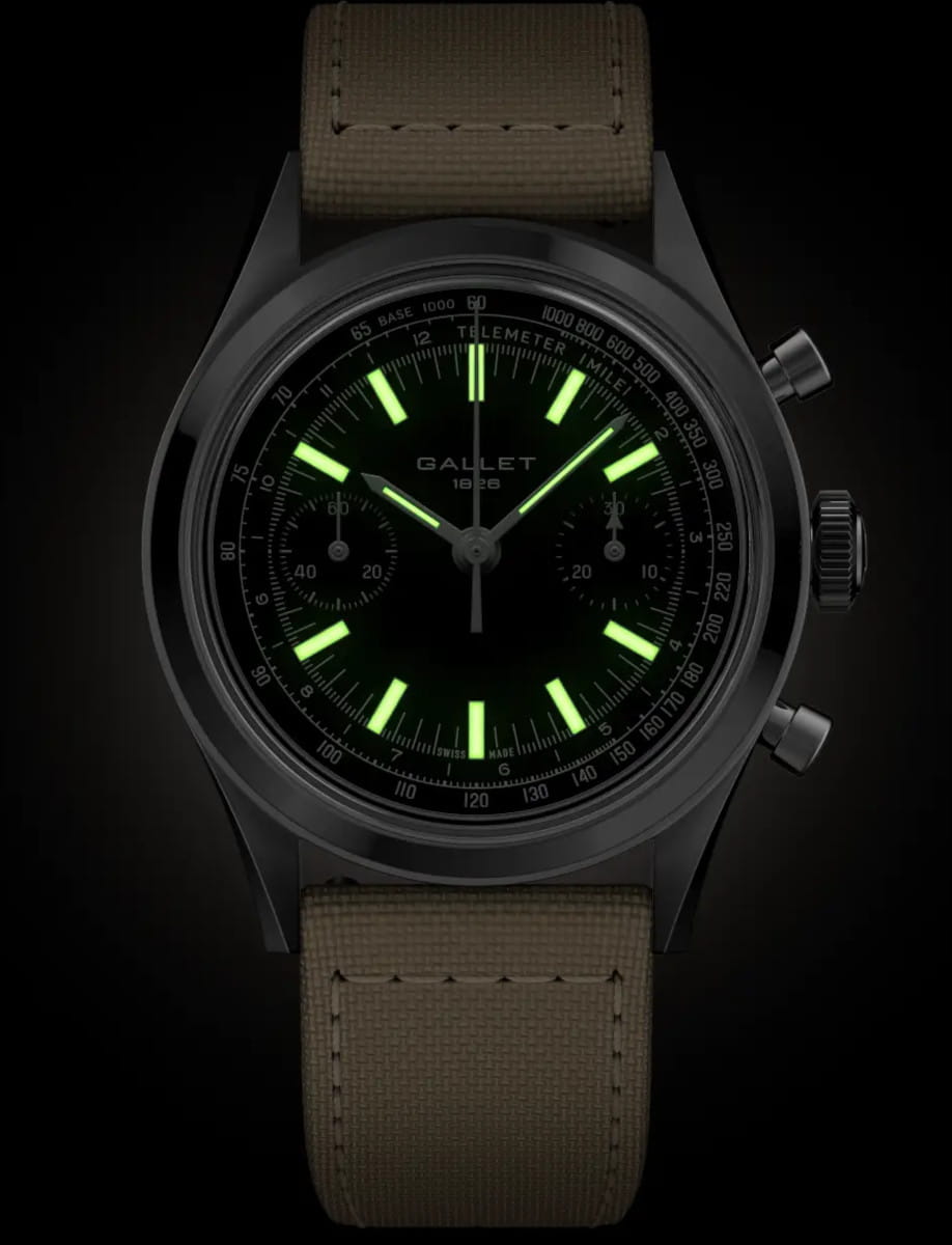 Luminous green markers and hands on a black dial Gallet wristwatch with a beige fabric strap and chronograph case. Readable in dark light.