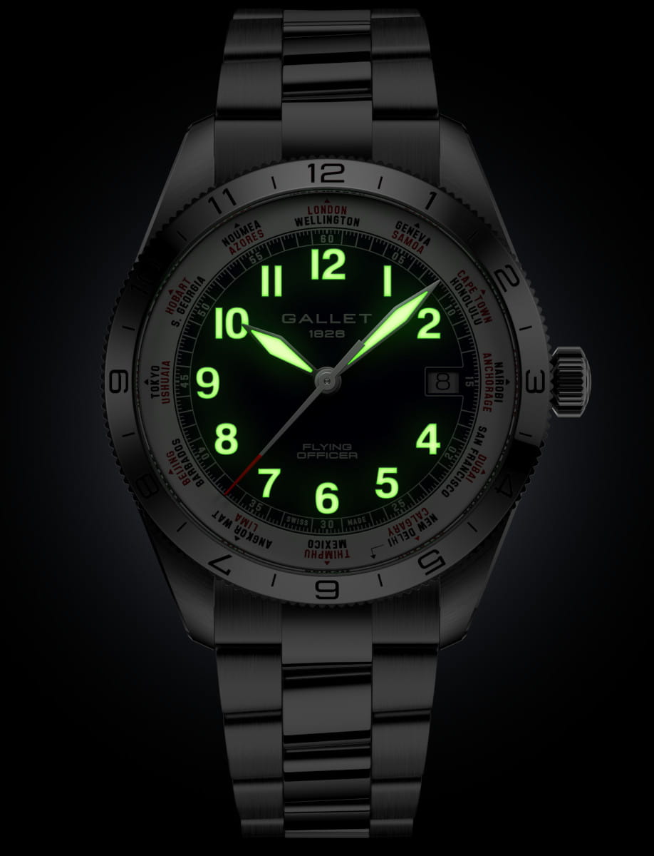 Stainless steel pilot’s watch with a black dial, glowing green numerals and hands, date window at 3, and a metal bracelet.
