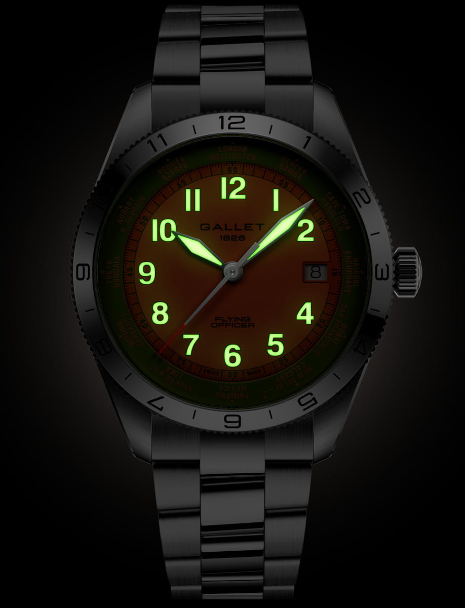 Stainless steel wristwatch with orange dial and glowing green numerals; date window at 3 o'clock and metal bracelet visible.