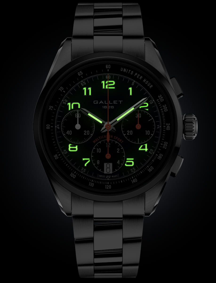 Gallet stainless steel chronograph watch with glowing green numerals on a dark dial and steel bracelet, showing date window at six o'clock.