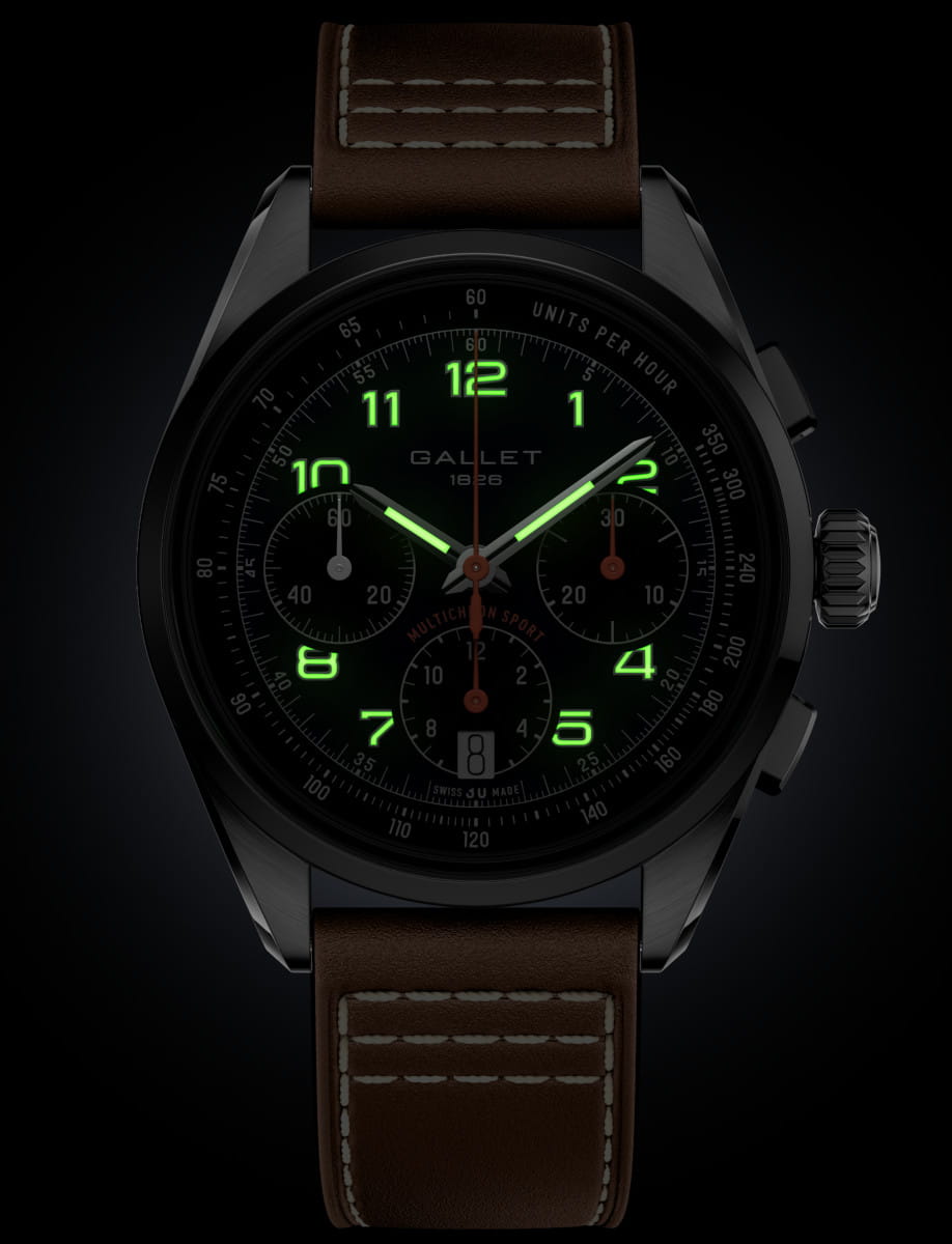 Gallet black chronograph watch with glowing green numerals and a brown stitched leather strap on a black backdrop